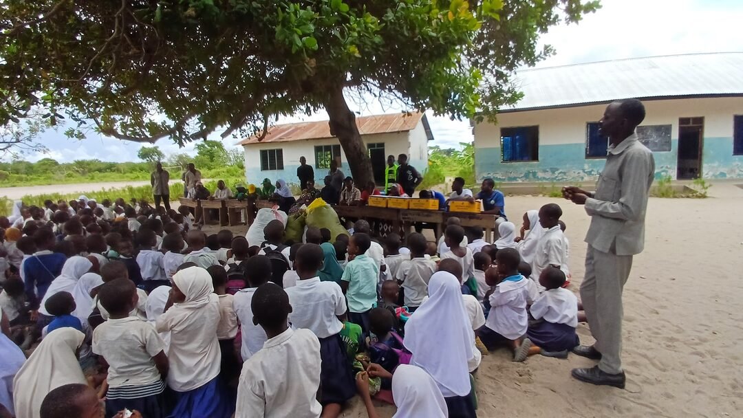 Foundation team speaking to pupils under a tree at school